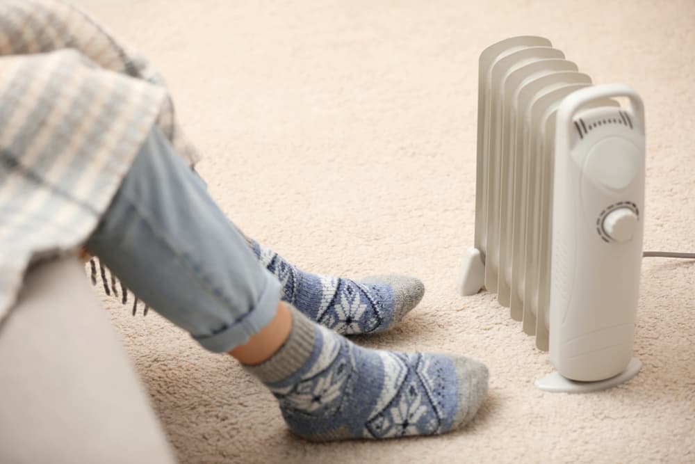 Person wearing socks sitting near a portable heater