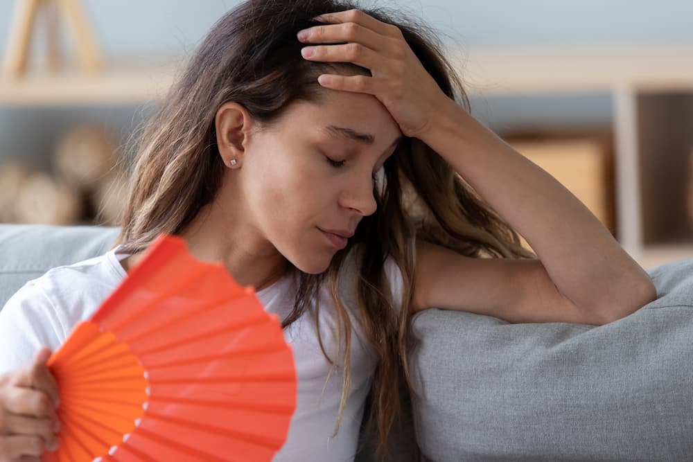 Woman fanning herself inside her home due to the air conditioning being out