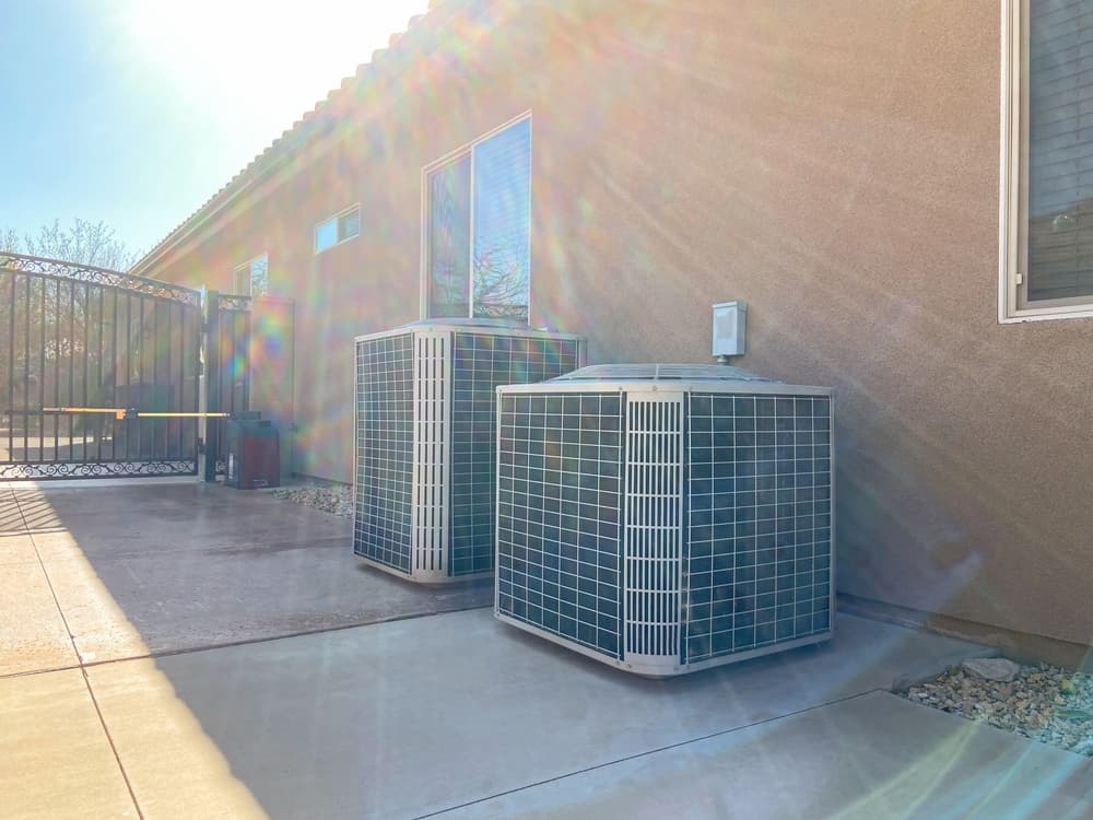 Two HVAC units outside on the side of a house.