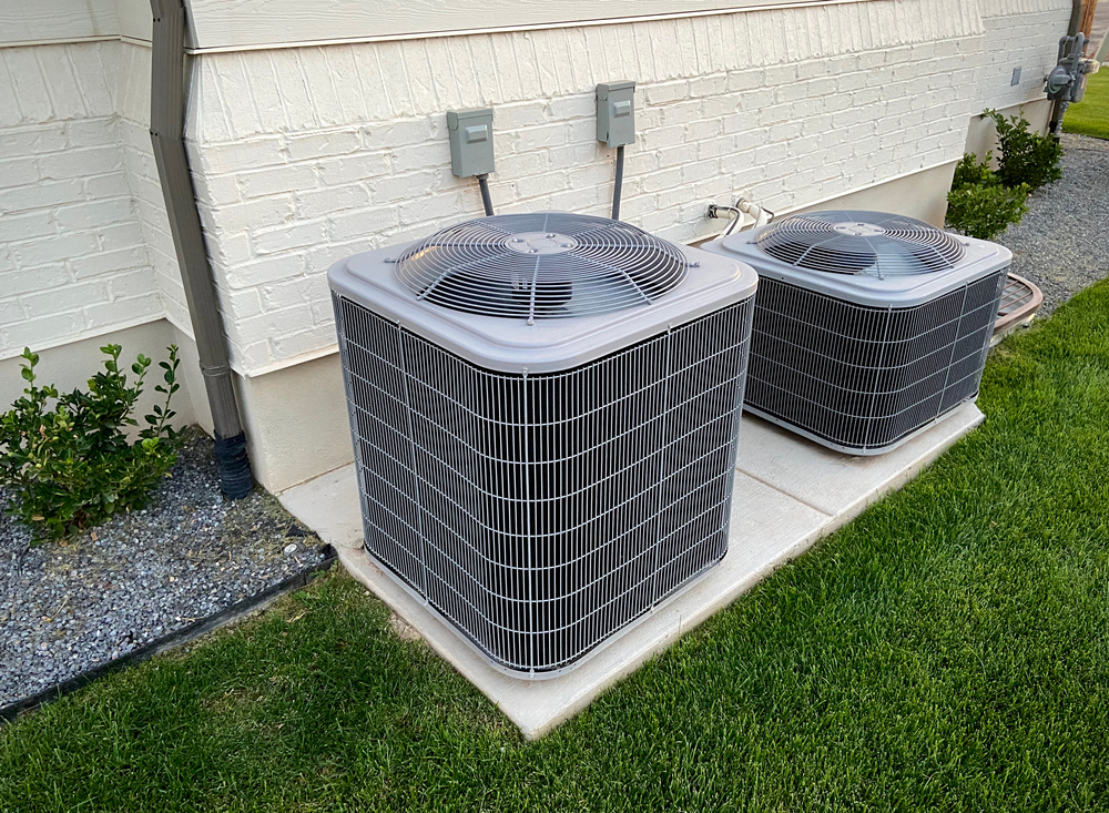 Two outdoor HVAC units on the side of a house