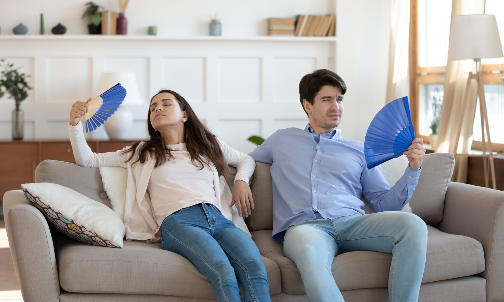 Stressed,Tired,Young,Family,Couple,Sitting,Together,On,Sofa,,Fanning